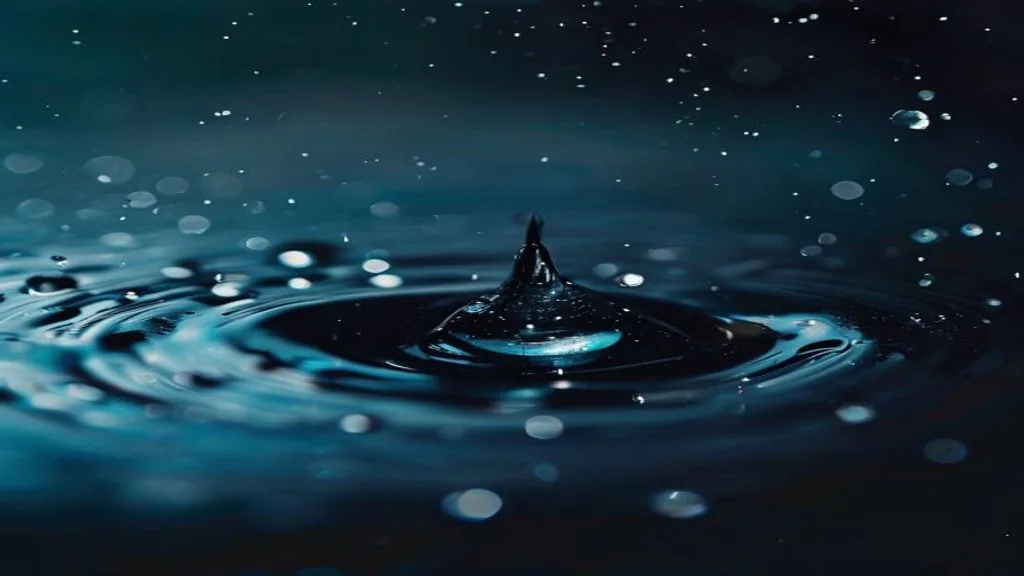 Abstract macro of a single droplet meeting a dark liquid surface