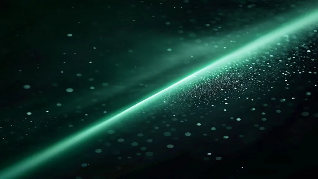 A single thin beam of green laser light grazing a wisp of pale vapor on a matte black surface