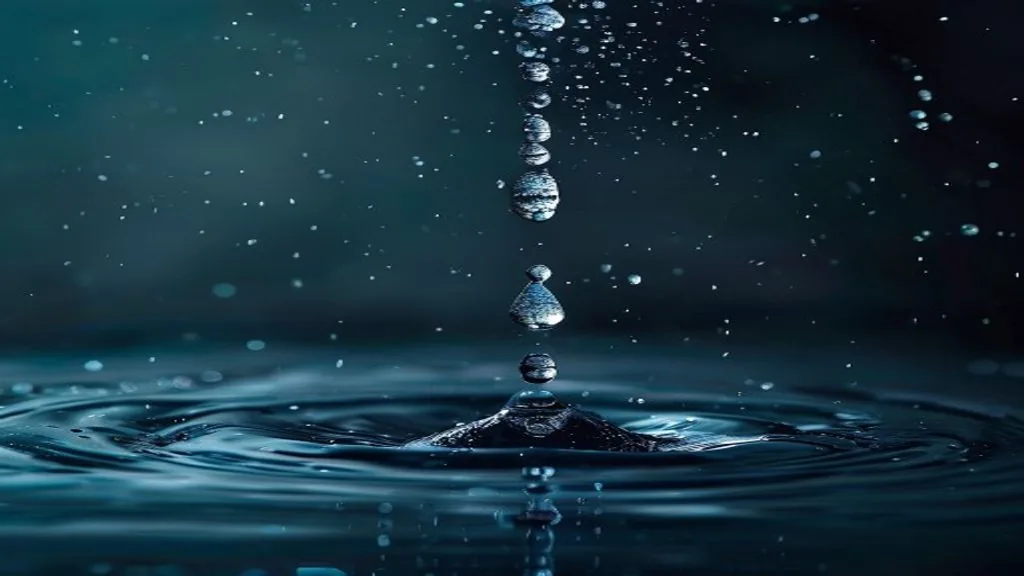 A single droplet of water frozen mid-fall against a dark background, with a shallow ripple below