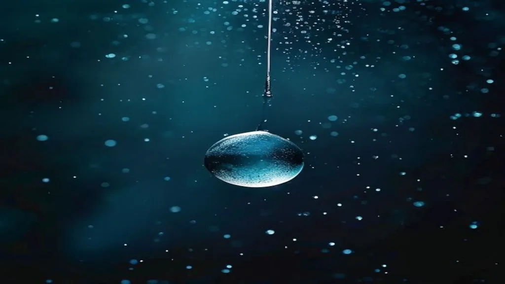 single suspended water droplet caught by a narrow beam of light against a deep black background